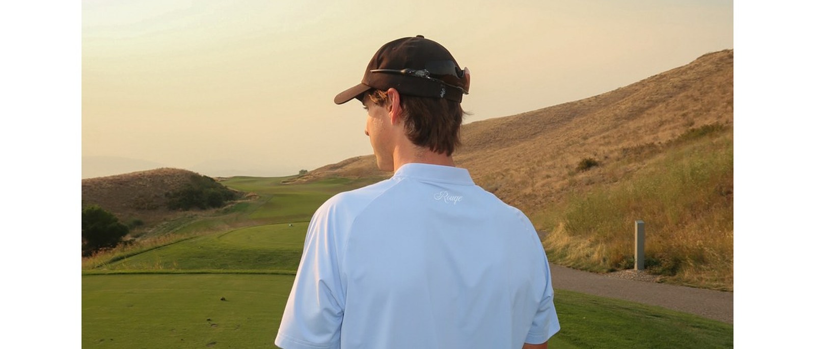 A golfer in the Rouqe Golf Blue Blade Collar polo on a dry hillside course, from the brand’s own campaign