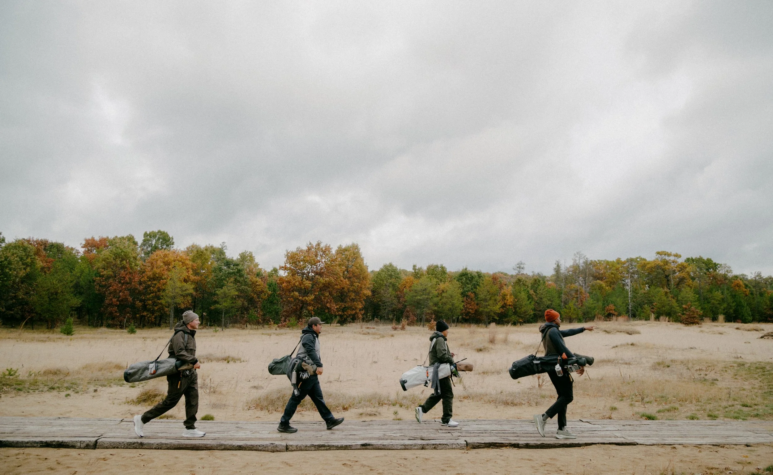 Four walkers on the boardwalk at Sand Valley, autumn treeline behind