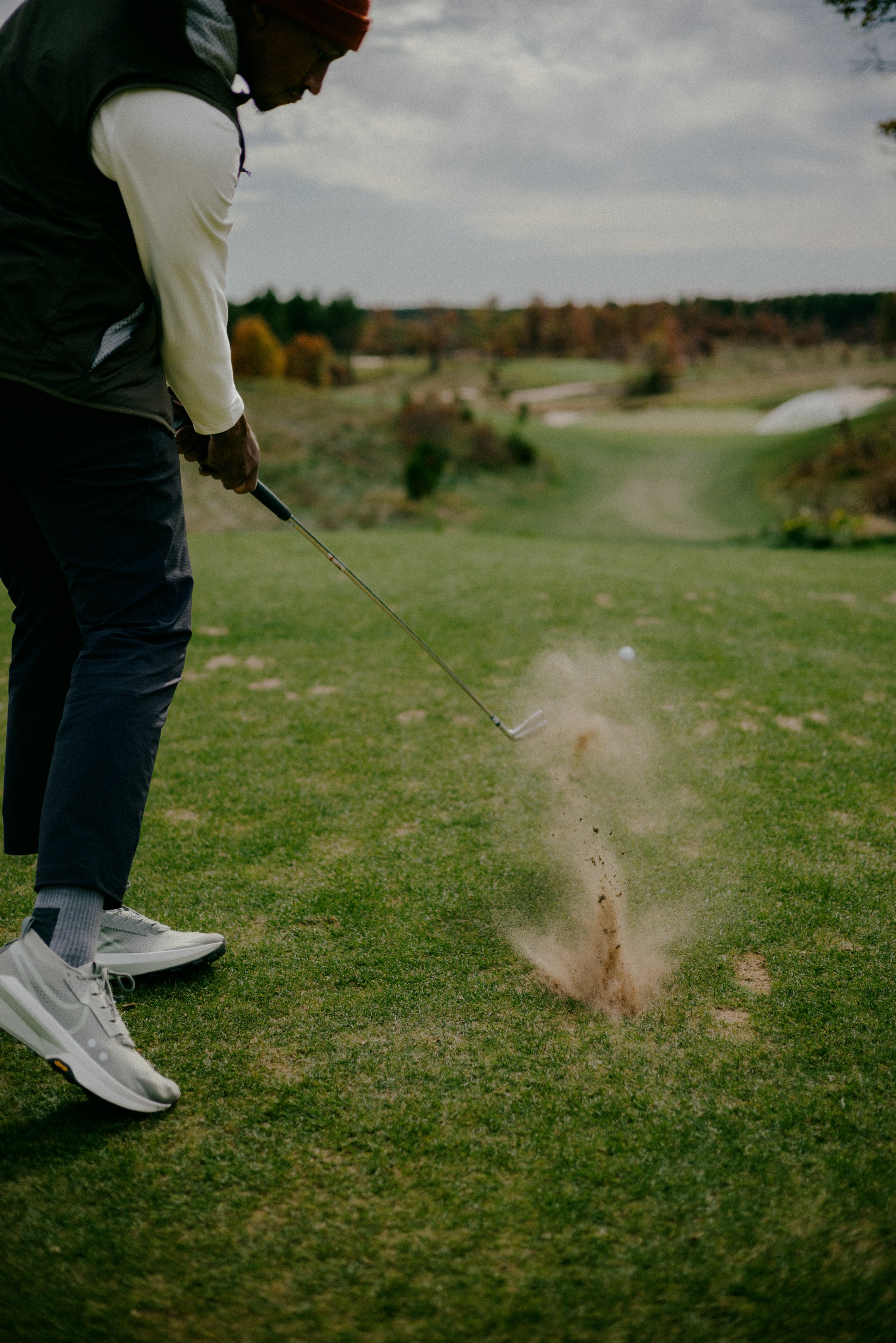 A wedge shot spraying sand, Sand Valley fairway beyond