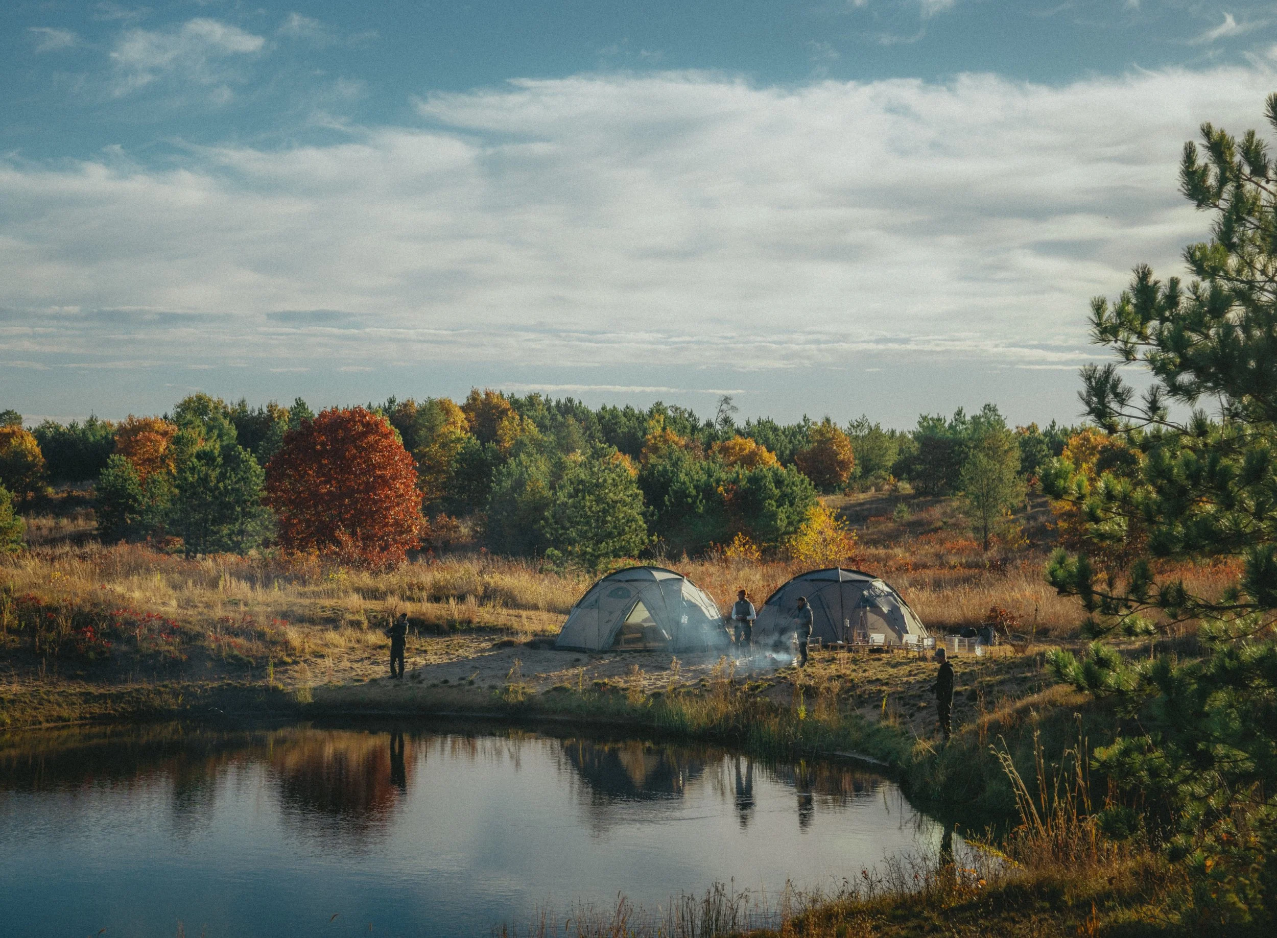 Two Basecamp domes mirrored in a pond under autumn colour