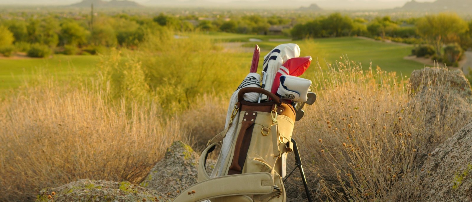 A Tan Shoal Standard Bag among desert grass and boulders above a golf course at sunset
