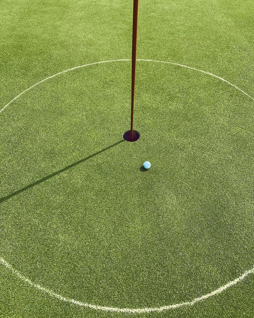 A flagstick and ball on a green