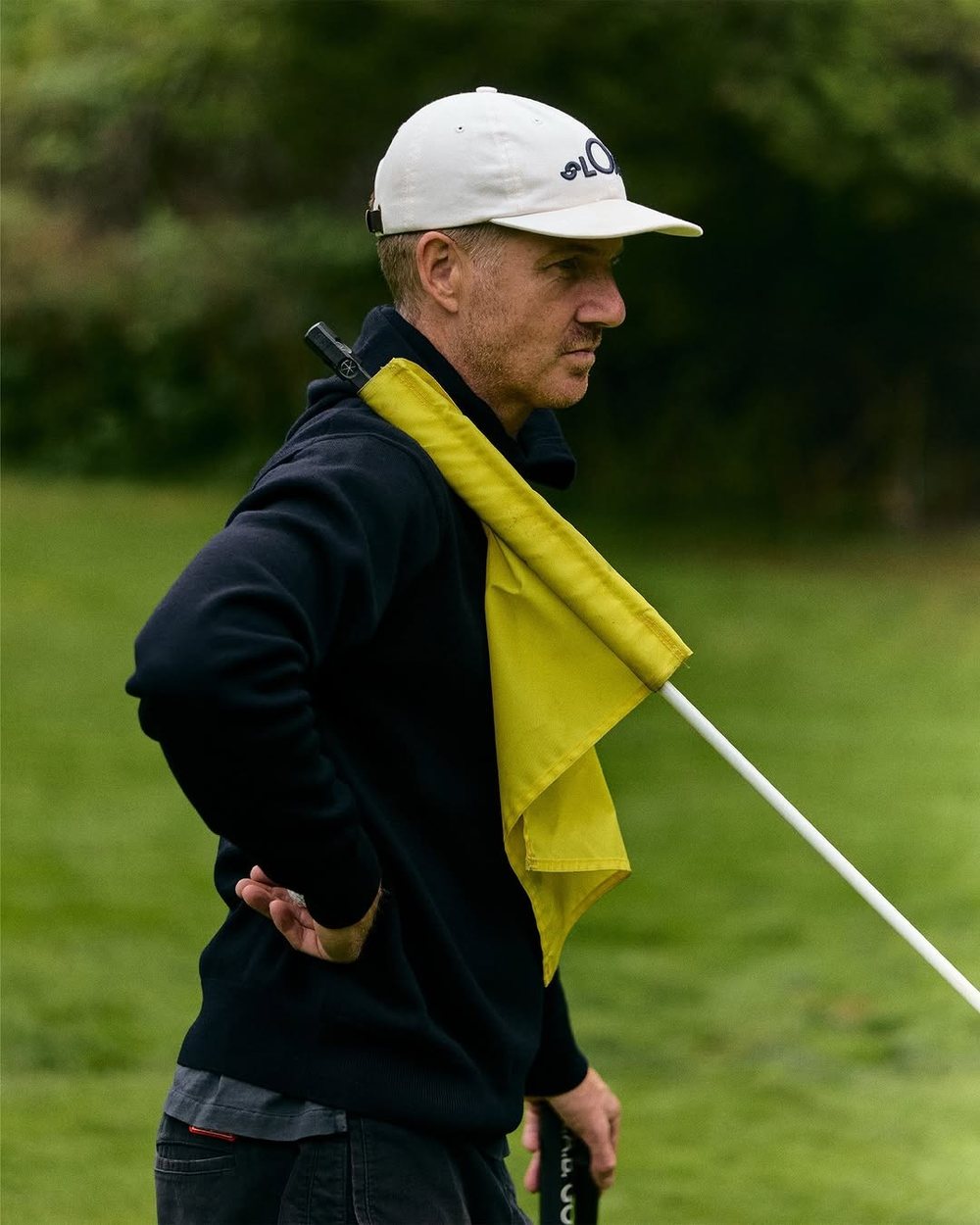 SLOAT co-founder Dan Fibiger holding a yellow flag in a navy quarter zip and white cap