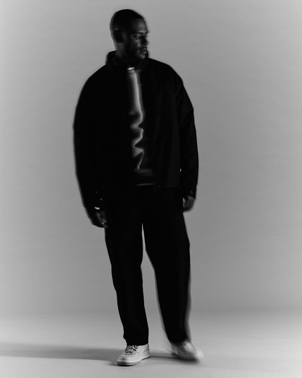 Black-and-white full-length portrait in a dark jacket and trousers