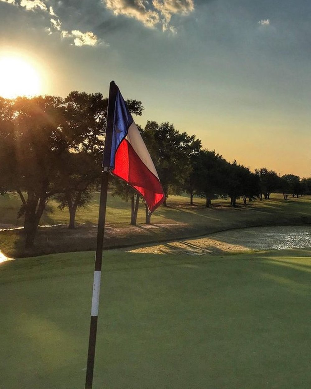 A Texas flag on a flagstick at sunset on an Austin municipal course