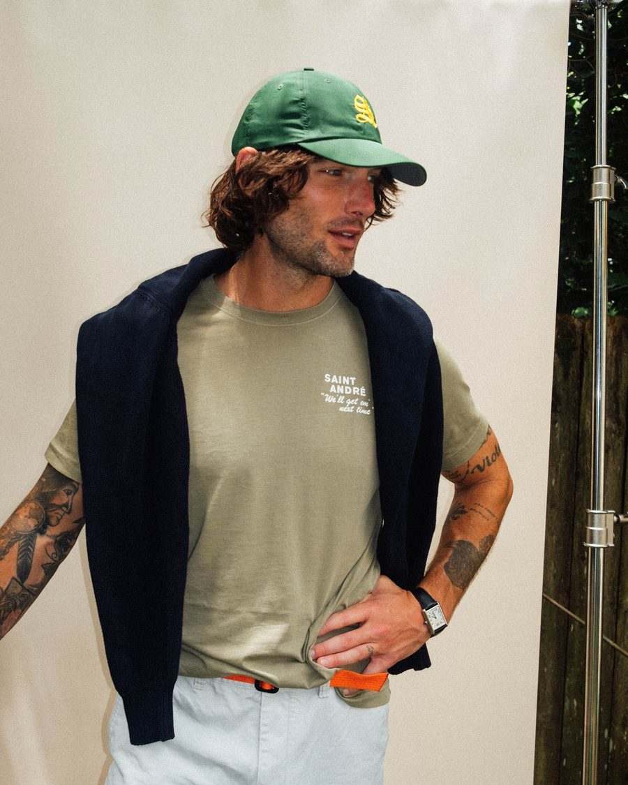 A man in a green St. André cap with a navy sweater over his shoulders