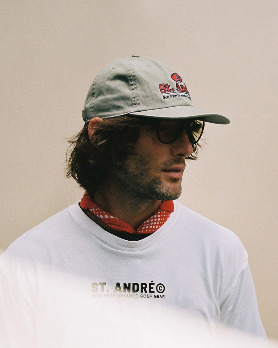 A man in a white St. André tee and a grey cap