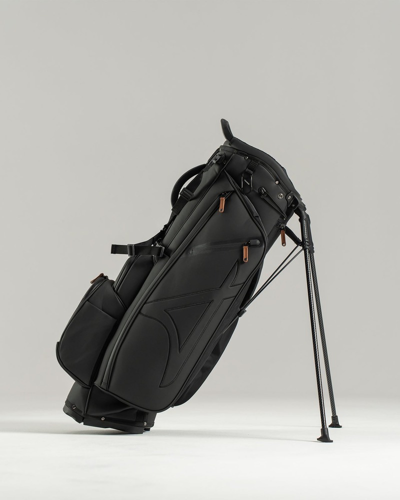 Takomo Stand Bag 02 in off-white laid on fairway grass beside clubs and golf balls