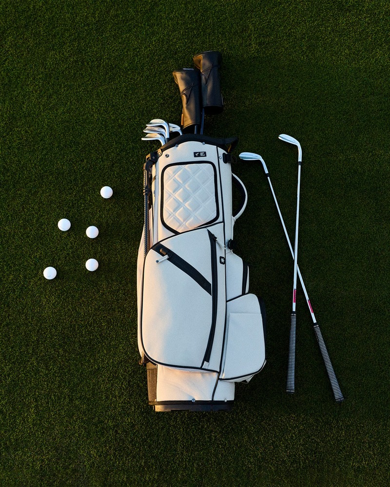 Takomo Stand Bag 02 in off-white laid on fairway grass beside clubs and golf balls