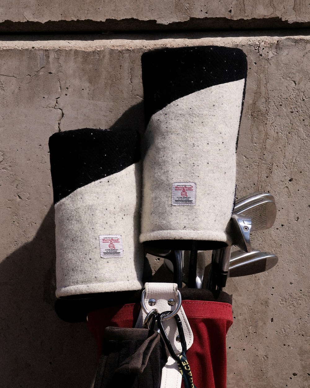 Two No Return Club Harris Tweed headcovers on clubs in a bag against concrete