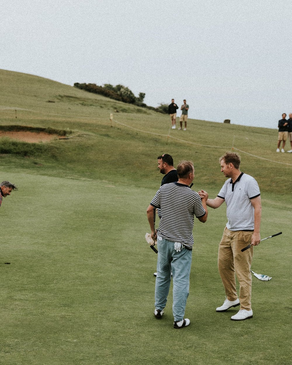 Four golfers in Sounder shaking hands on a links green