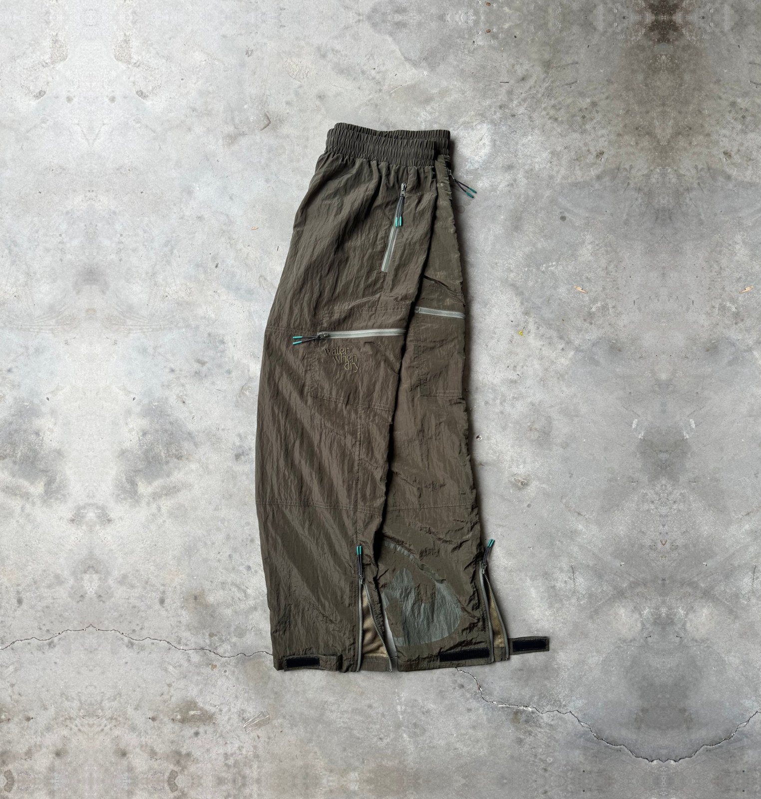 Green utility pants laid flat on concrete