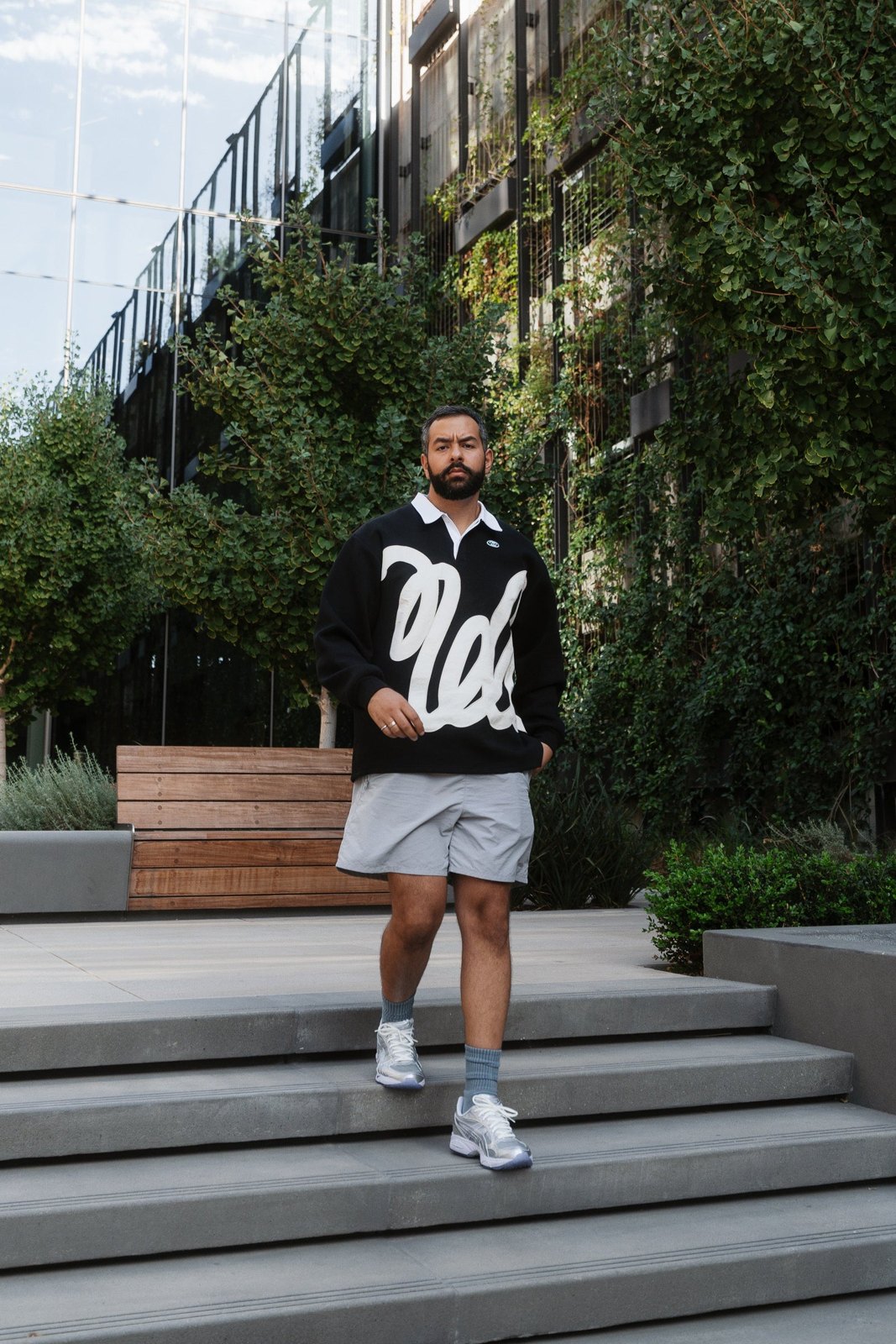 A man in the black pullover and grey shorts walking down concrete steps
