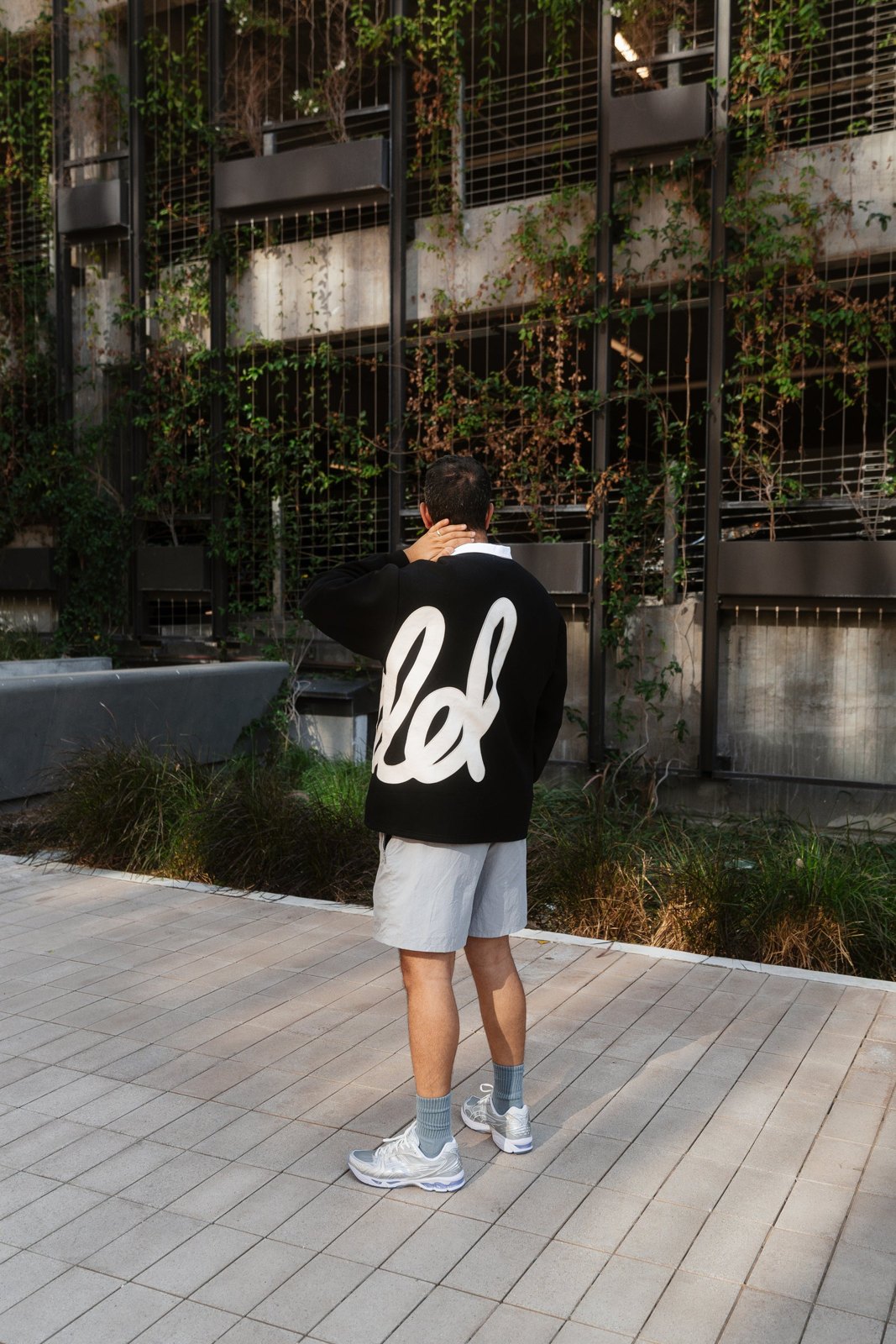 A man in the black pullover seen from behind, with the script across the back