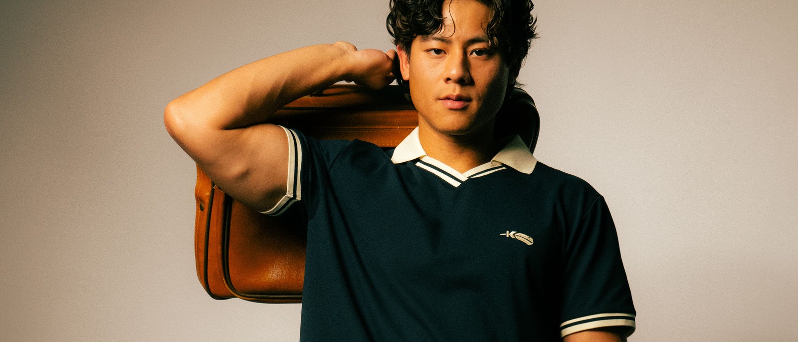 A golfer carrying a leather bag in a Kingfisher Golf polo, the Dallas menswear label founded by Fiona Cohen
